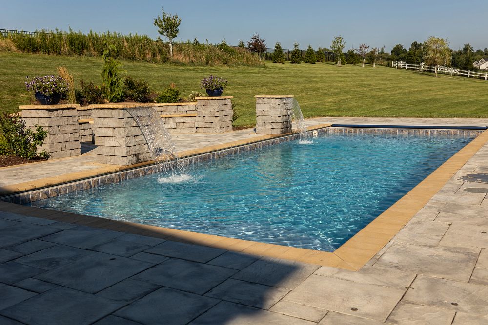 fiberglass pool with custom water features in sloped backyard