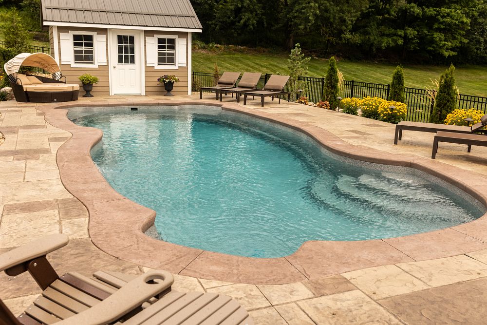 freeform fiberglass shape pool in backyard with lounge chairs