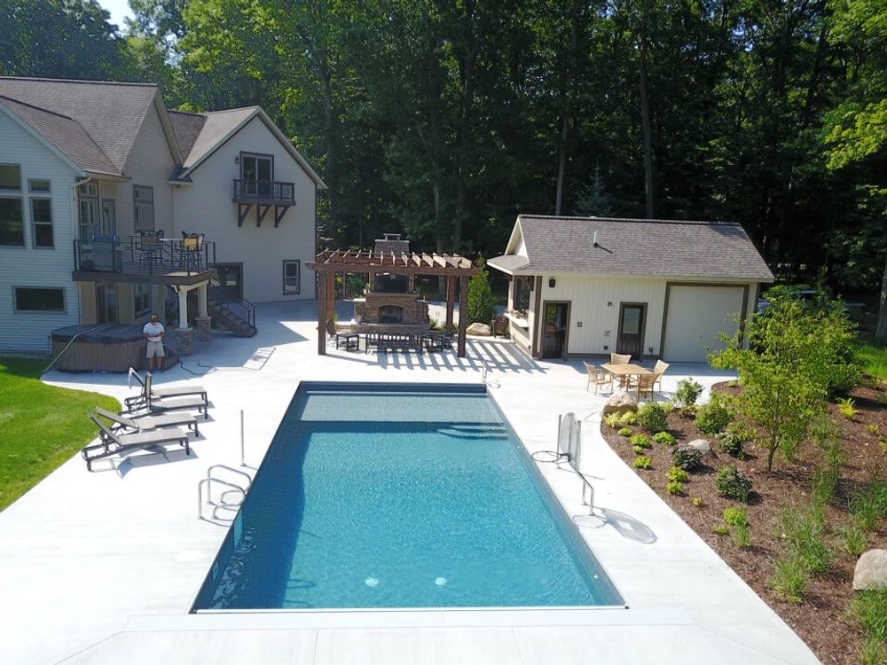Gray Mosaic Custom Shape Vinyl Liner Pool From Latham Pool with white deck, pergola, and fireplace