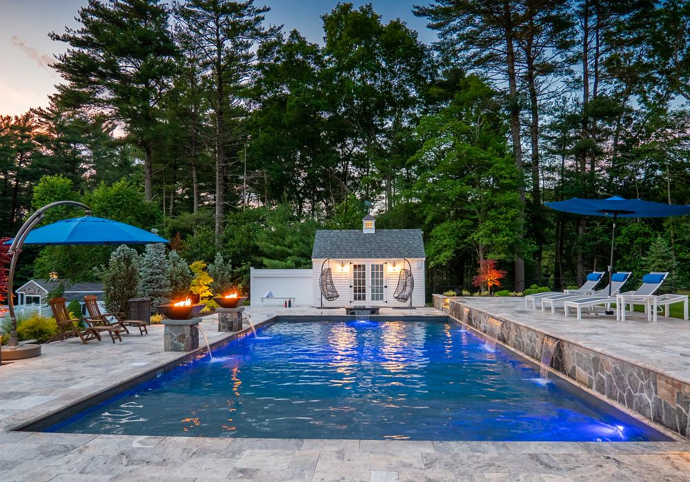 modern rectangular vinyl liner pool surrounded by a gray stone patio with patio furniture and fire bowls with water fountains