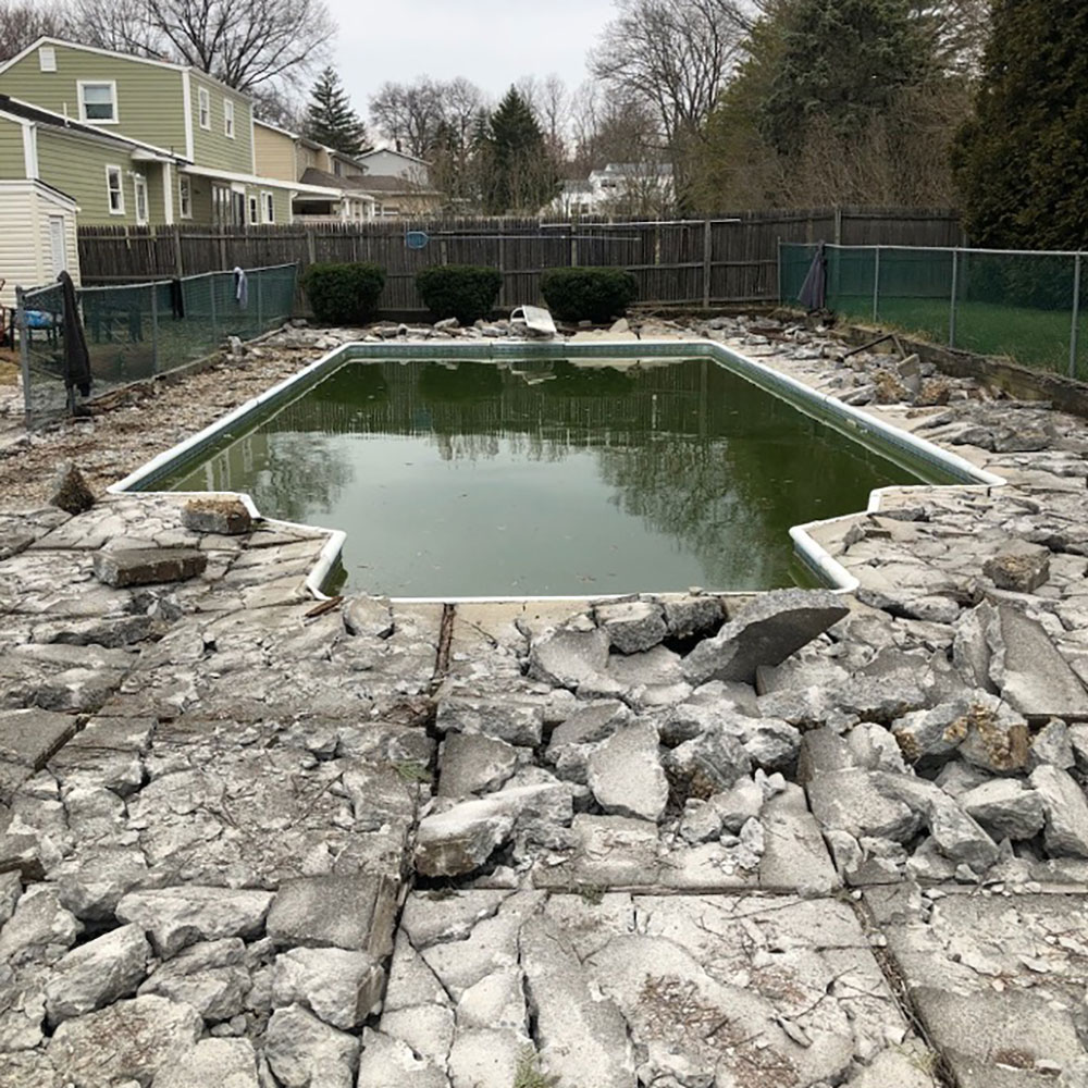 Rectangle vinyl liner pool with broken concrete floors surrounding it