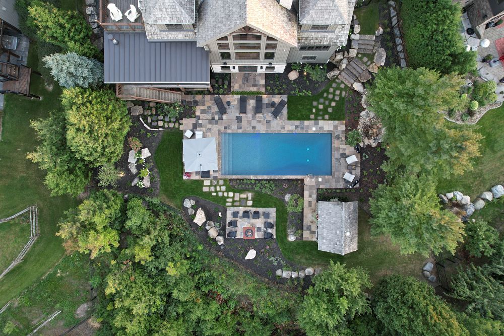 Sky view of a house backyard, including a rectangle pool and manicured landscaping