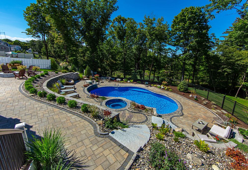 vinyl liner pool with a spa and patio furniture on a sloped backyard