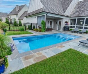rectangular pool in small backyard with stone pavers and patio furniture