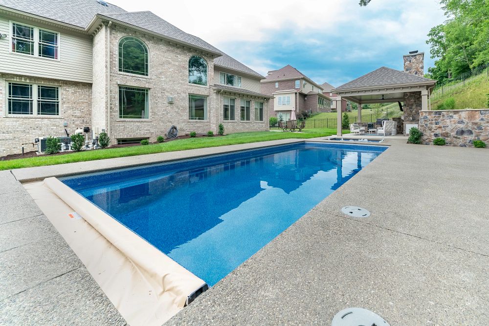 rectangular pool with autocover surrounded by a concrete patio