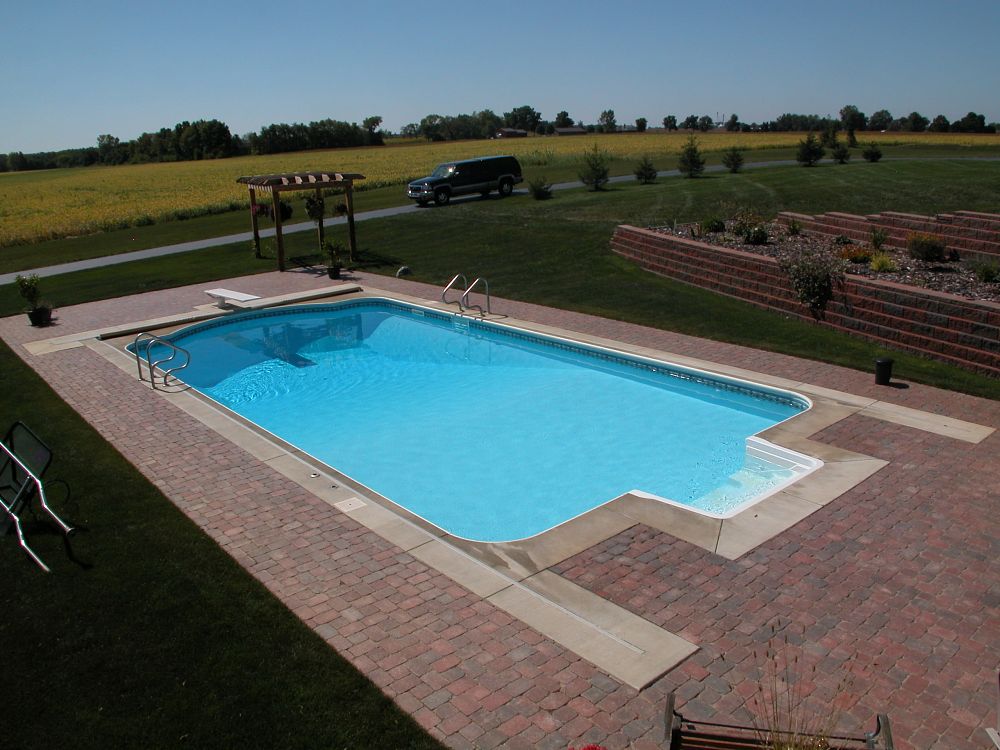 rectangular shaped pool with concrete and brick pavers
