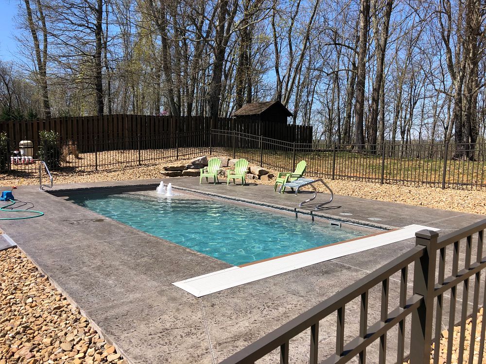 rectangular shaped pool with concrete deck and tan rock perimeter