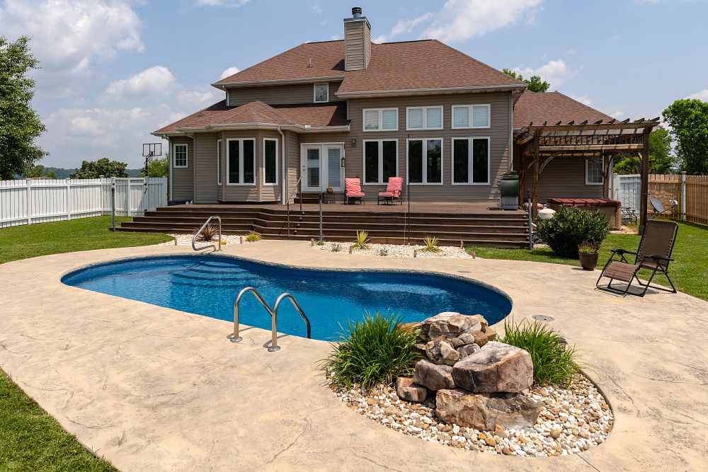 kidney shaped fiberglass pool in wide open backyard