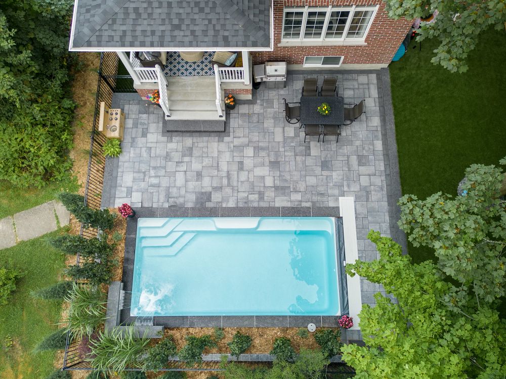 small rectangular pool surrounded by landscaping and a paved patio