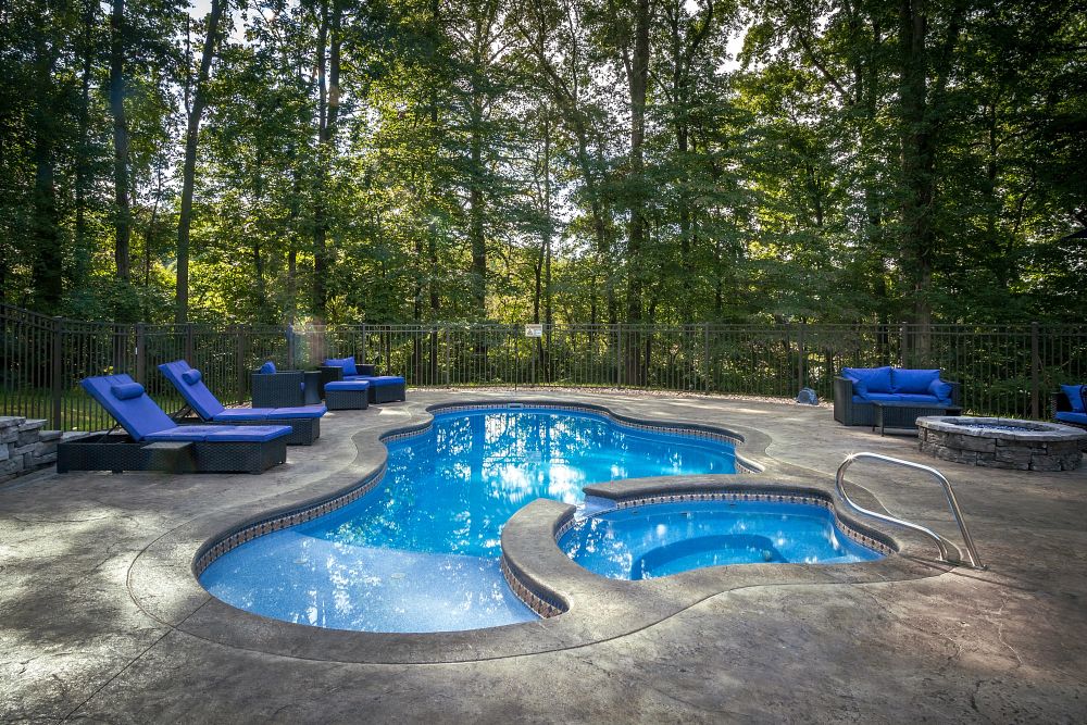 freeform fiberglass pool and spa surrounded by safety fence