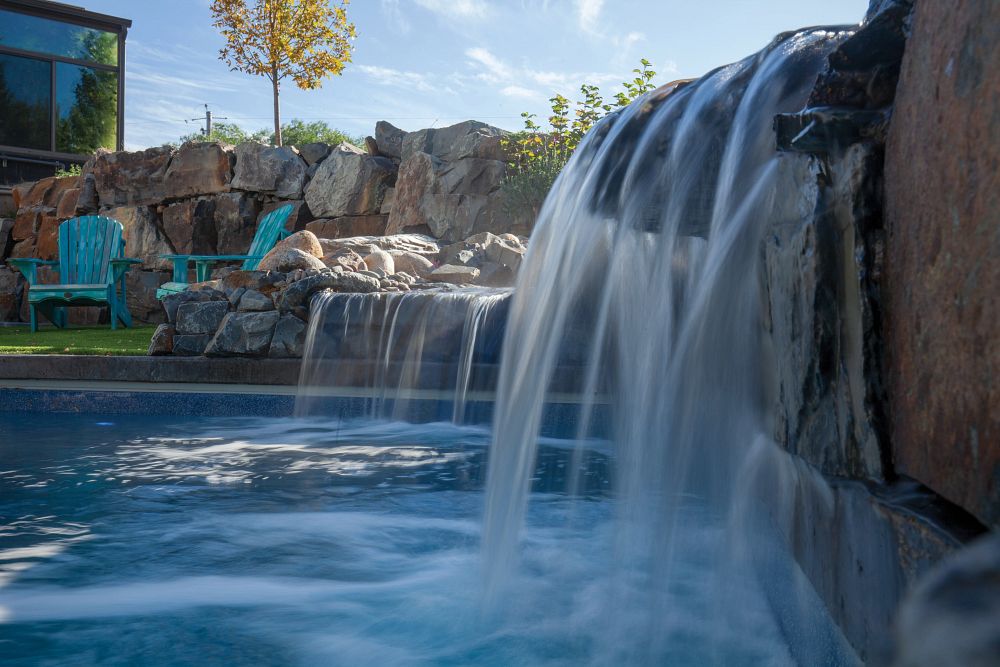 Two waterfalls on the edge of a backyard pool as a pool design idea