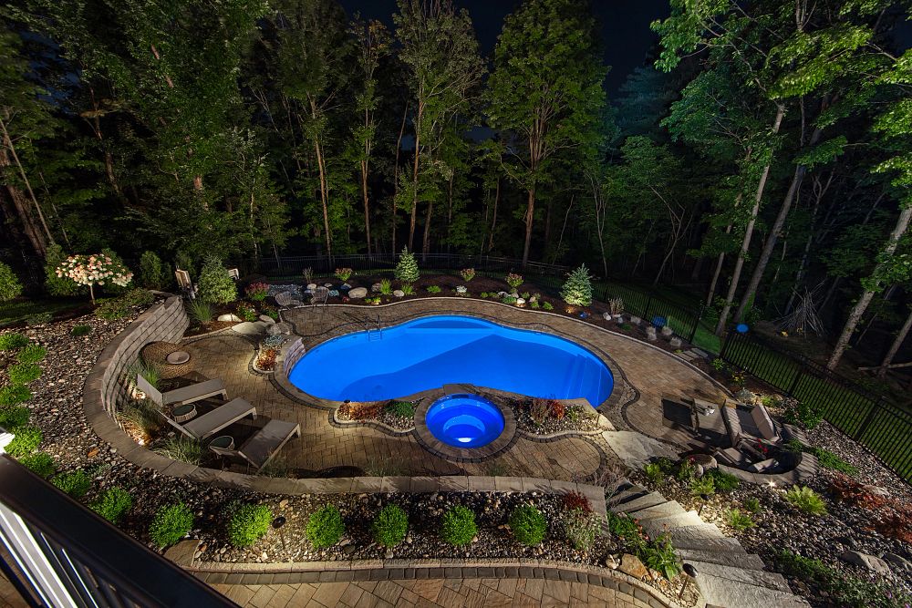 aerial view of freeform pool shape with spa in sloped backyard