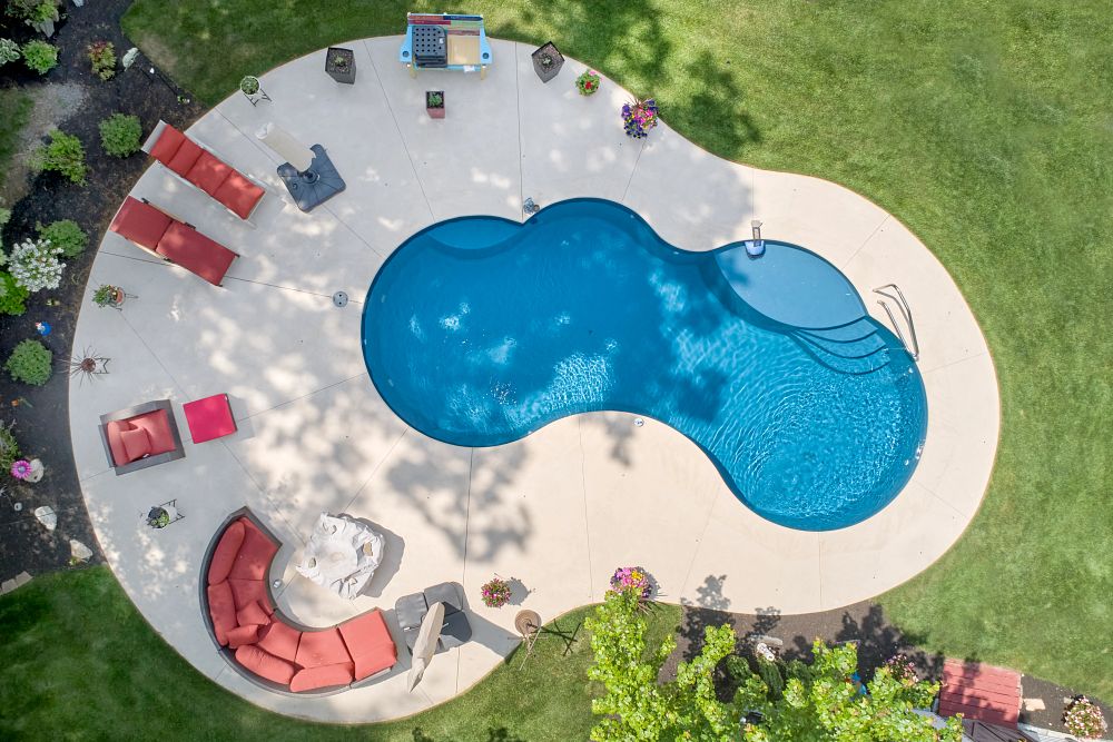 Aerial view of a backyard pool with cushioned patio furniture