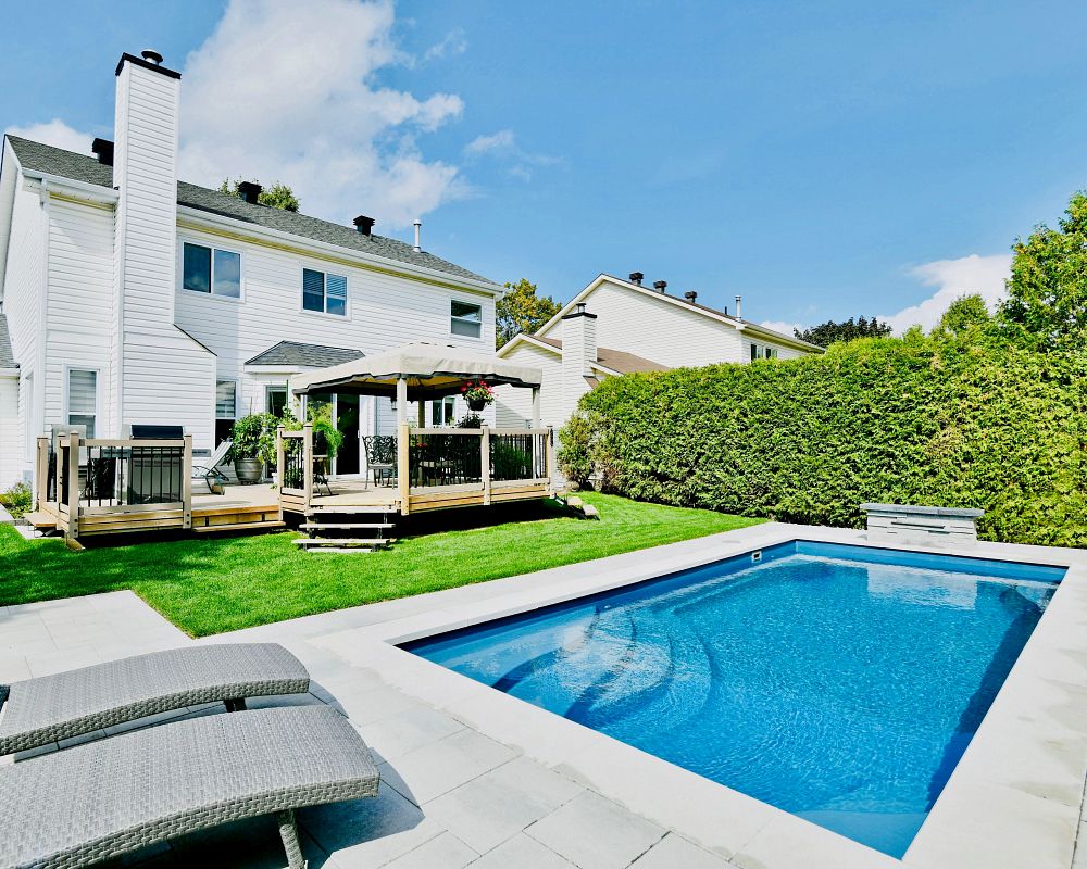 rectangular pool in backyard surrounded by a tall hedge for privacy