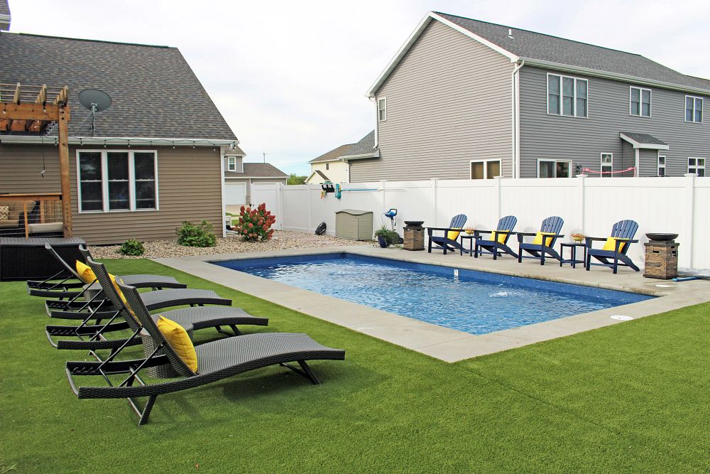 Rectangle fiberglass pool with decking, grass, and lawn furniture