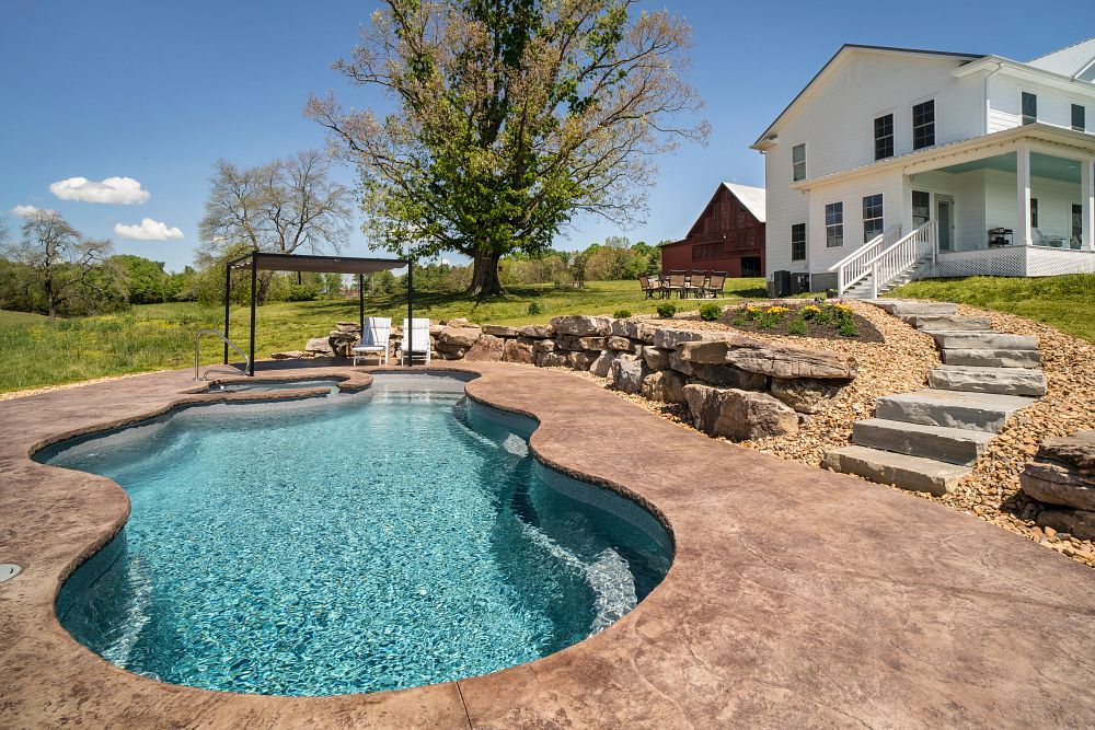 freeform shaped fiberglass pool in a sloped backyard