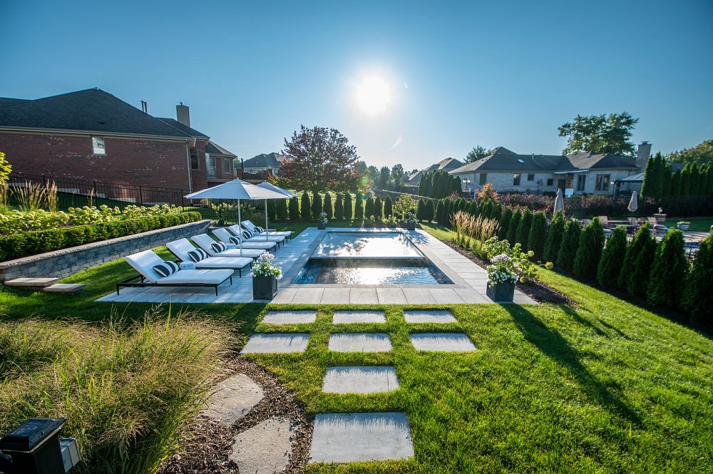 small, rectangular shaped pool in Illinois backyard with lounge chairs and umbrellas