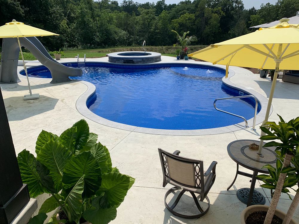 curvy vinyl liner pool in Ohio backyard with waterslide and spa