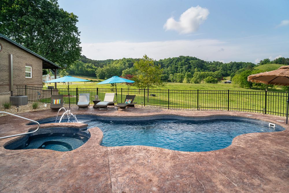 freeform fiberglass pool in backyard with spa and custom water features