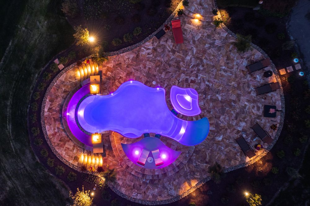 birds eye view of fiberglass pool in large backyard with custom coping & firepits