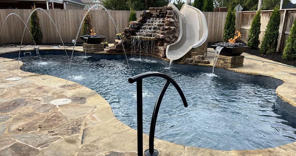 fiberglass pool in Tennessee backyard with custom water features, waterslide, and fire pits
