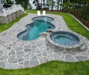 Fiberglass pool and spa with custom water feature in southern backyard.