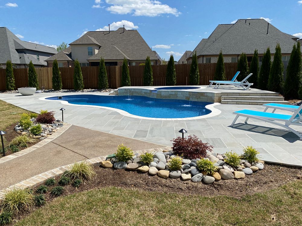 compact fiberglass pool with spa and custom water features in small suburban backyard