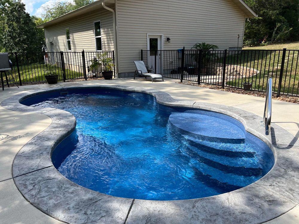 freeform fiberglass pool built on a hill in an uneven Missouri backyard