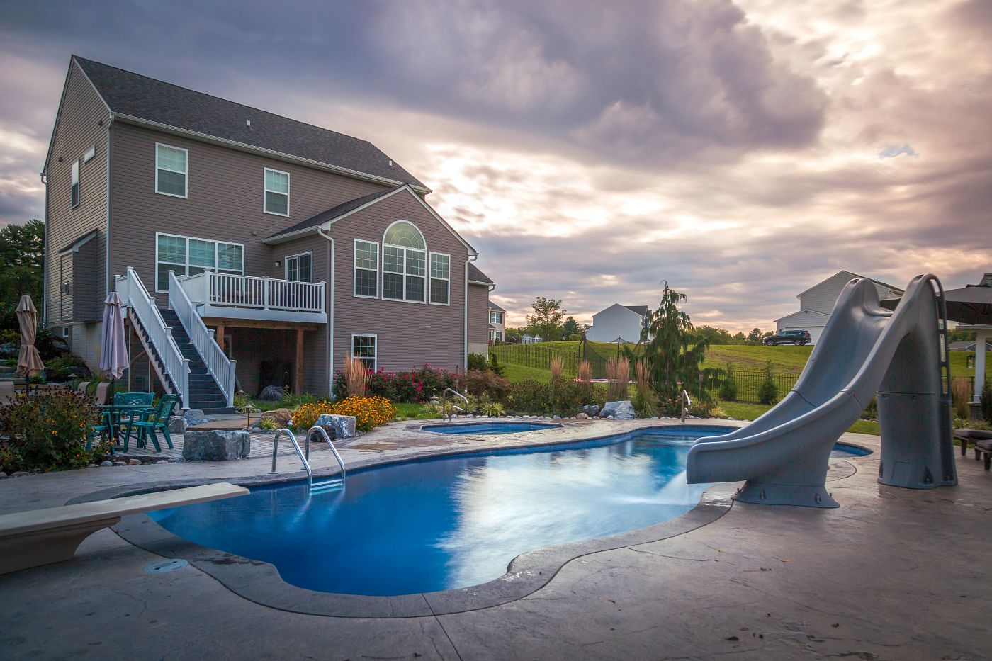 large fiberglass pool with spa, waterslide, and diving board in northeast backyard