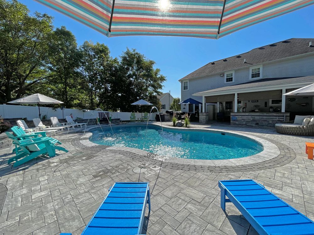 curved vinyl liner pool with custom water features in suburban backyard
