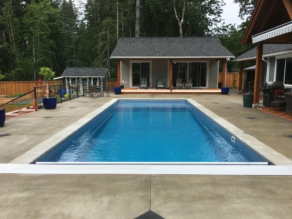 rectangular fibreglass pool with safety cover in British Columbia backyard