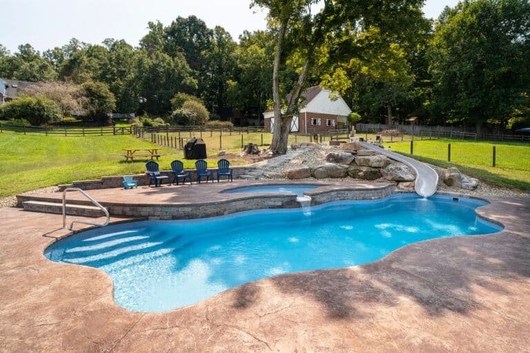 freeform fiberglass pool with waterslide, tanning ledge, and custom landscaping