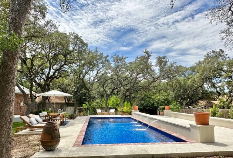 rectangular fiberglass pool with custom water features and nice landscaping