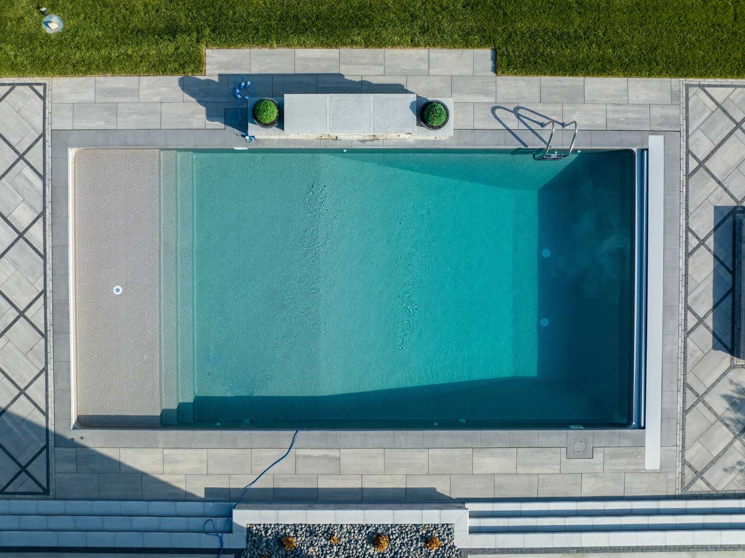 Overhead view of a rectangular vinyl liner pool with clear water and modern tile decking.