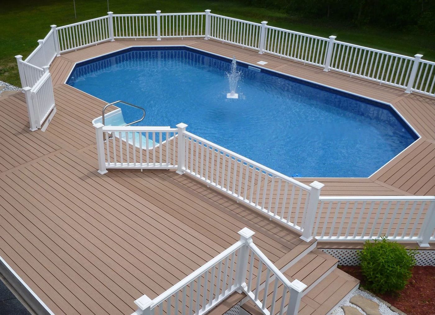 Octagonal vinyl liner pool surrounded by a wooden deck and white railing.