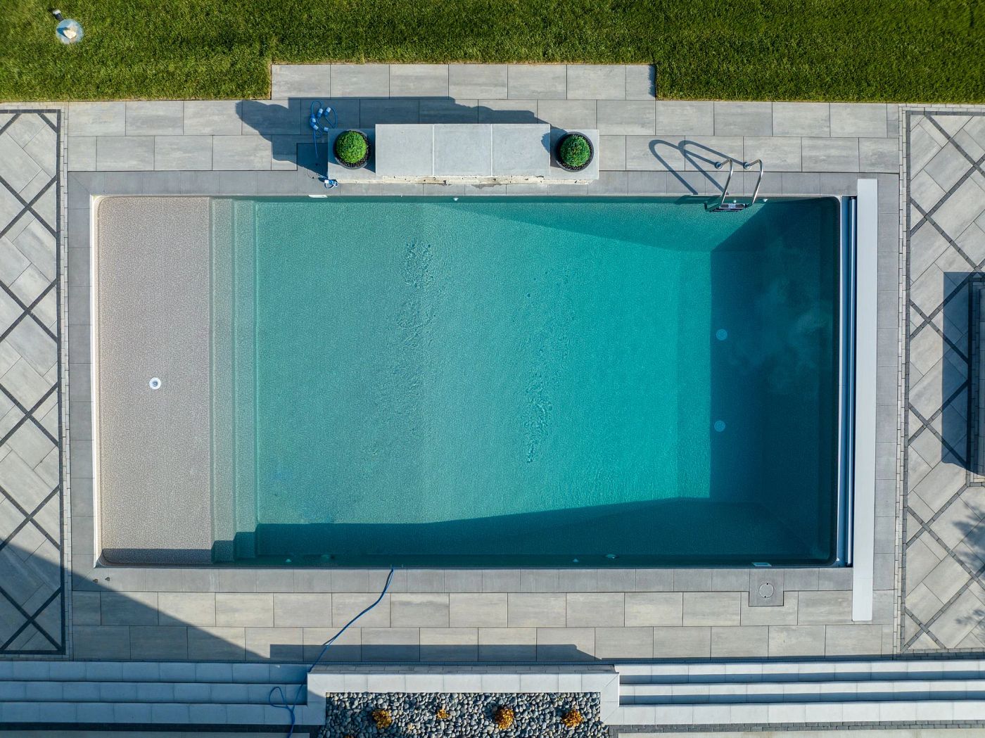 Overhead view of a rectangular vinyl liner pool with clear water and modern tile decking.