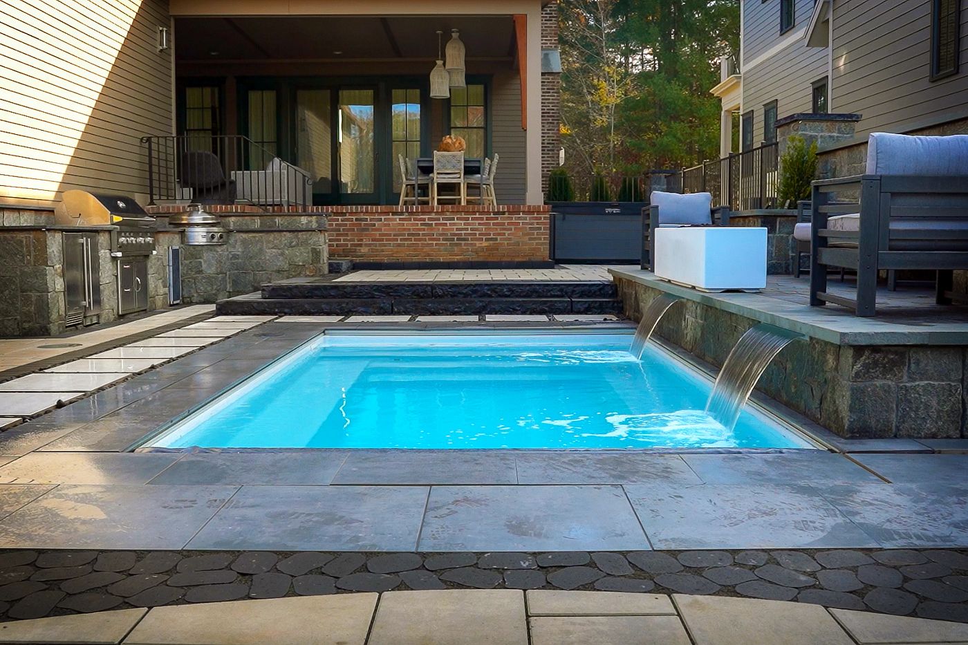 Compact plunge pool with modern deck and built-in waterfall feature.