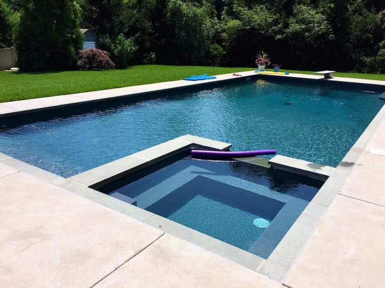 Rectangular vinyl liner pool with steps, set against a green lawn and landscaped garden.