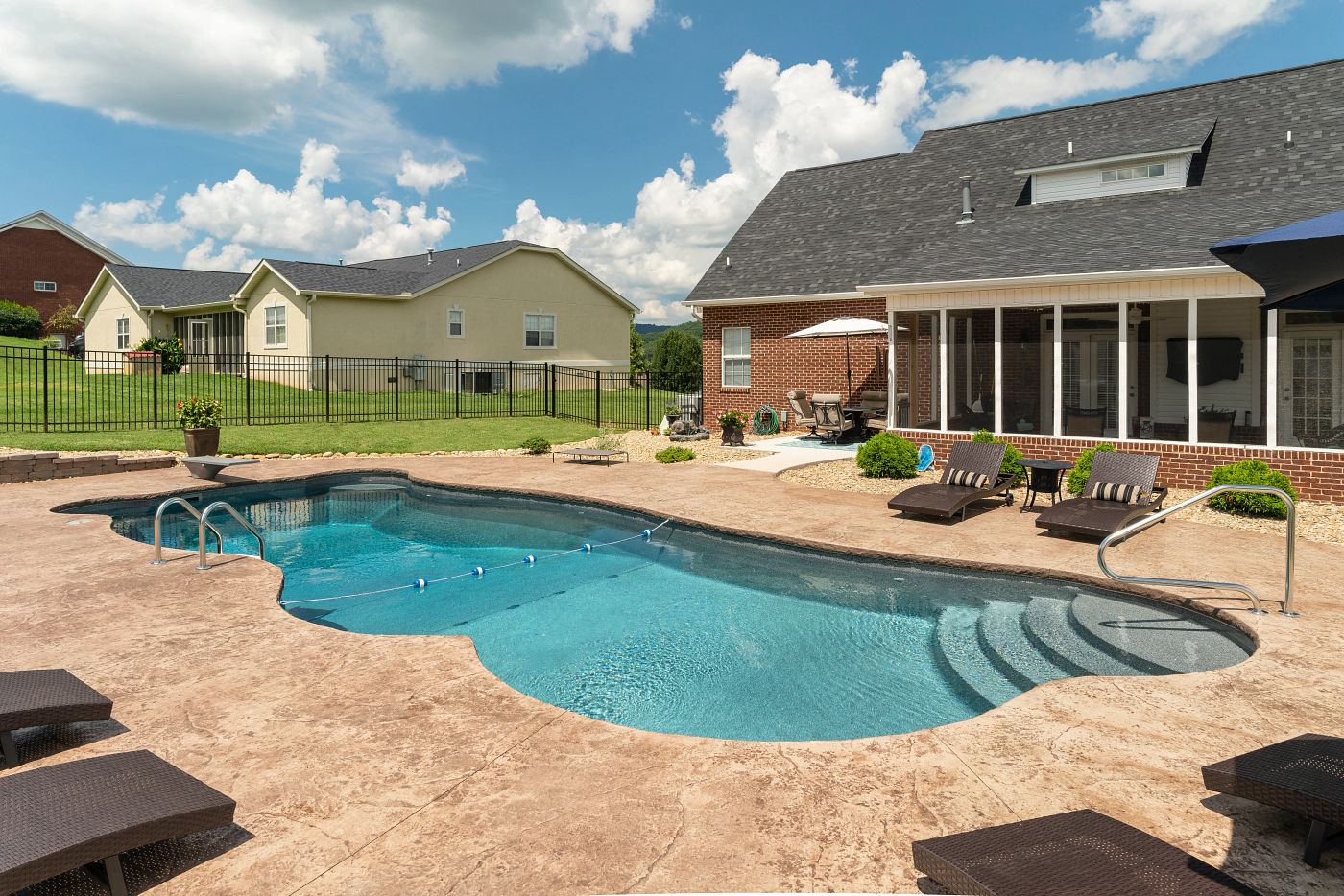 Freeform vinyl liner pool with textured blue liner, elevated stone accent wall, and perimeter decking.