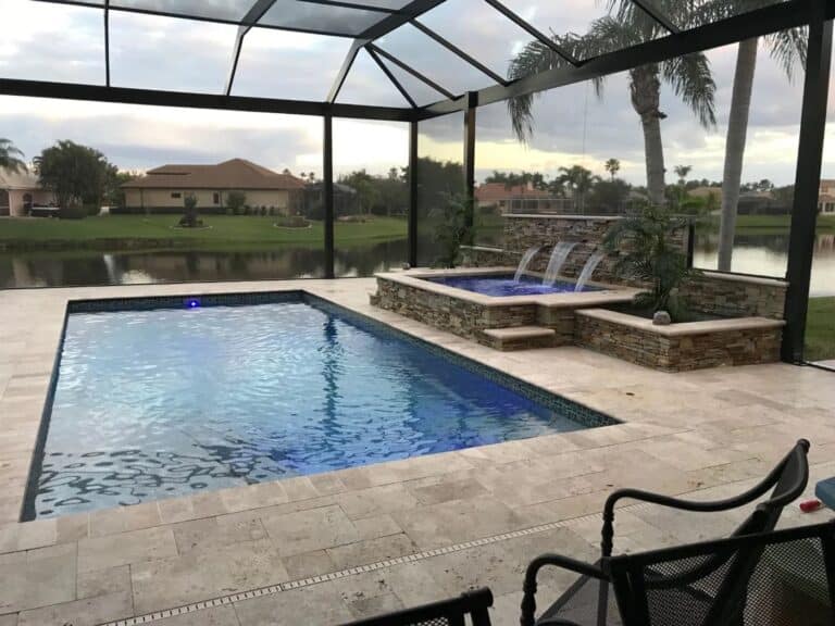 Rectangular fiberglass inground pool and elevated spa, enclosed by a screen, with a fountain feature.