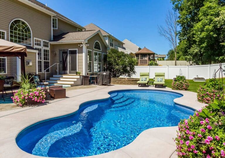 Freeform fiberglass pool in a fenced backyard setting